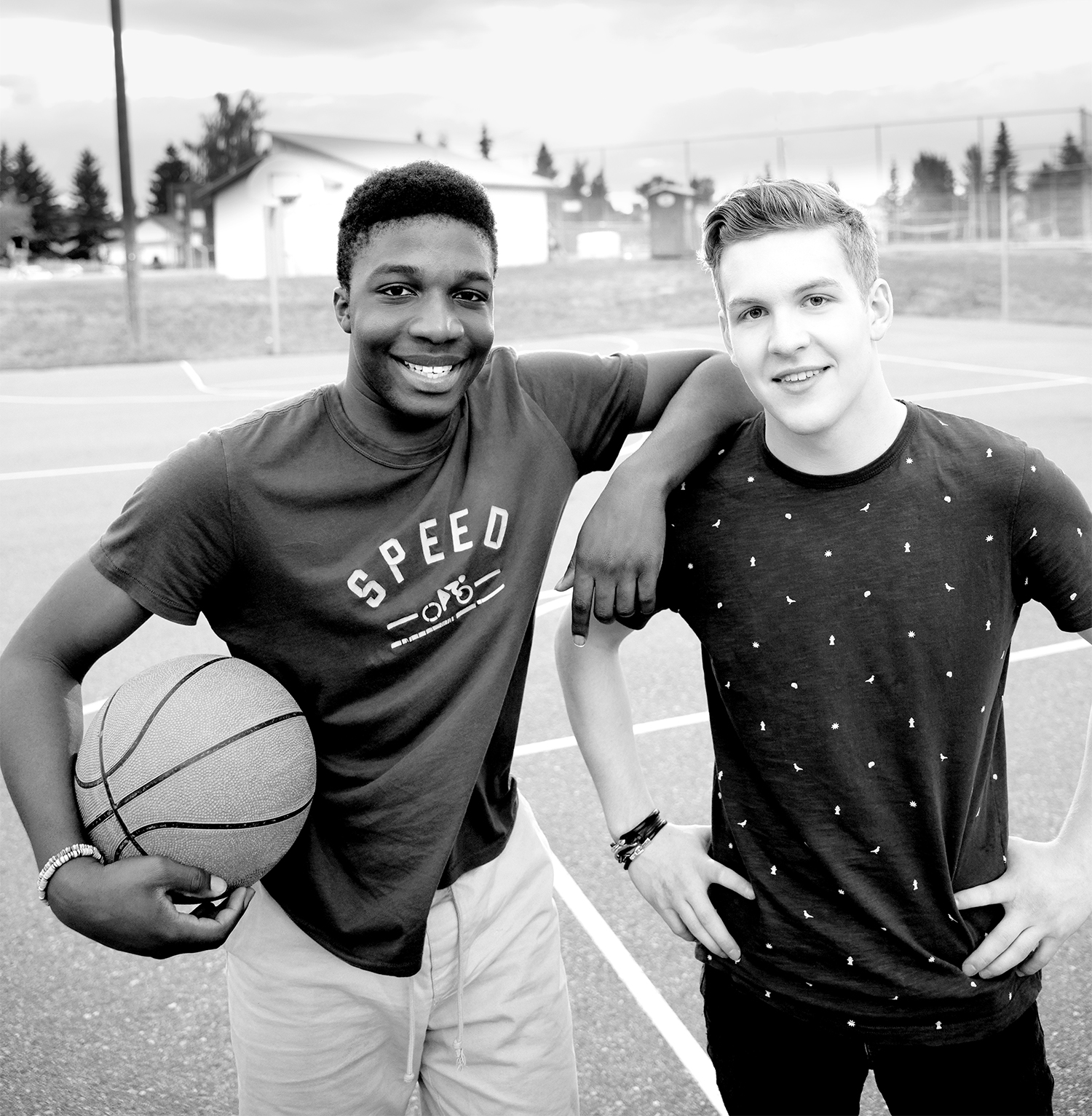 Portrait confident teenage boys with basketball on outdoor basketball court